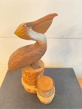 Handcrafted and hand painted wooden pelican statue sitting on dock pilings